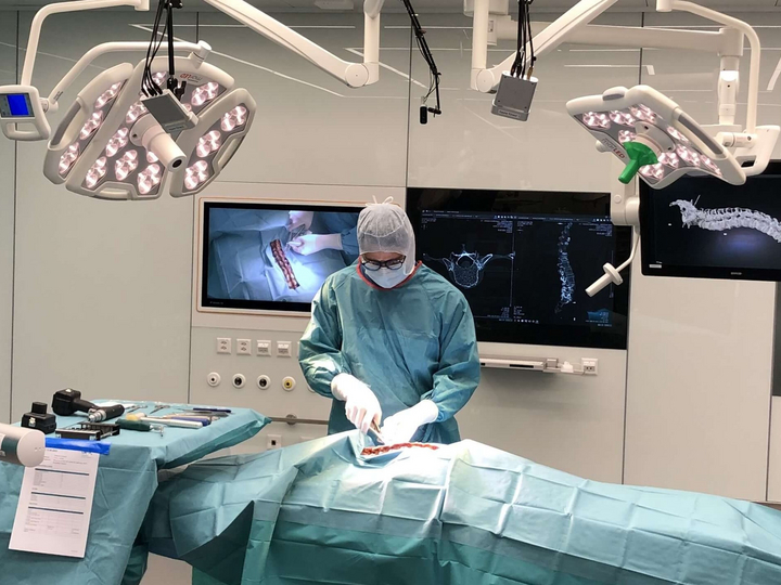 A surgeon working in an operating room on a spinal surgery.