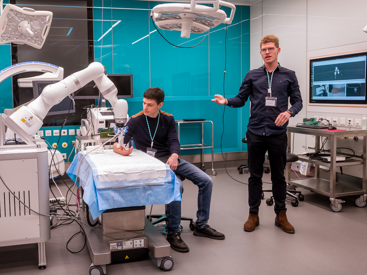 Two researcher explaining an ultrasound demonstration with a KUK robotic arm in the OR-X.