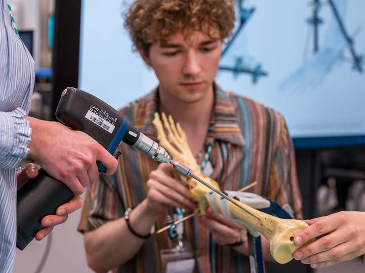  Medical students use a drill to insert a screw into an artificial lower leg.