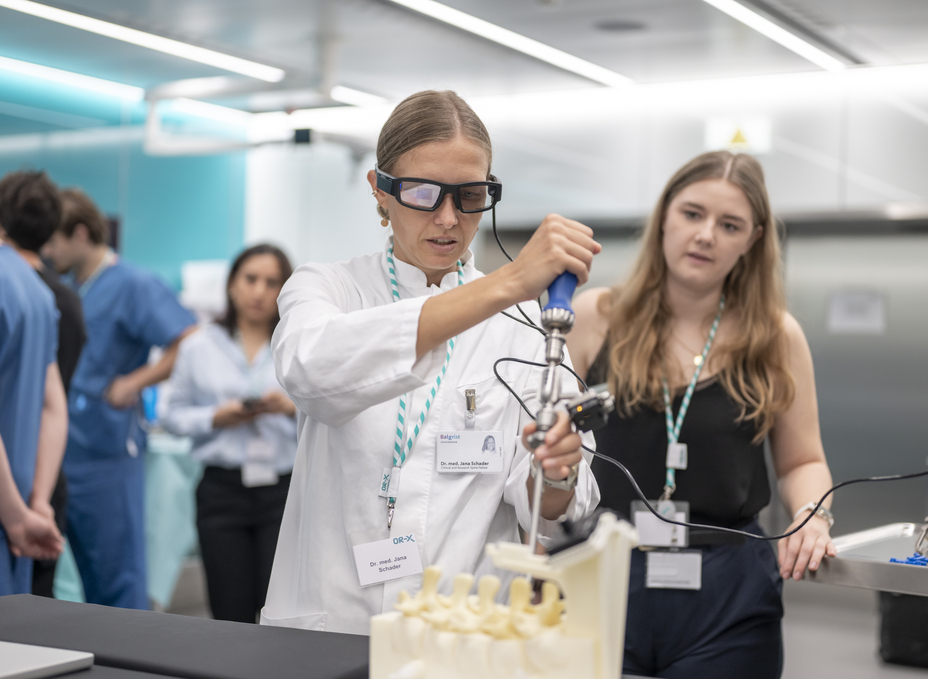 A surgeon wears AR glasses while inserting a screw into a spinal model using a surgical key.