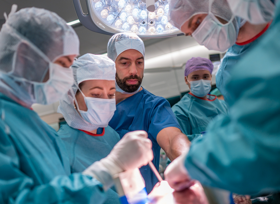 Group of residents working at an operating table while a senior surgeon gives them instructions