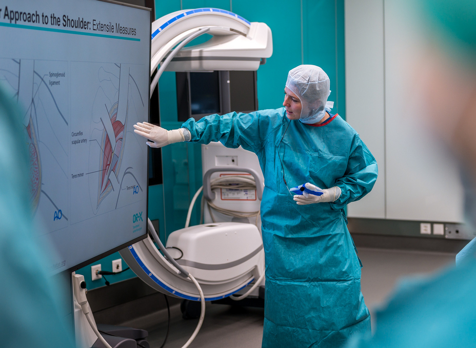 The senior physician uses an illustration on a screen in the OR-X to demonstrate how to place an access to the shoulder