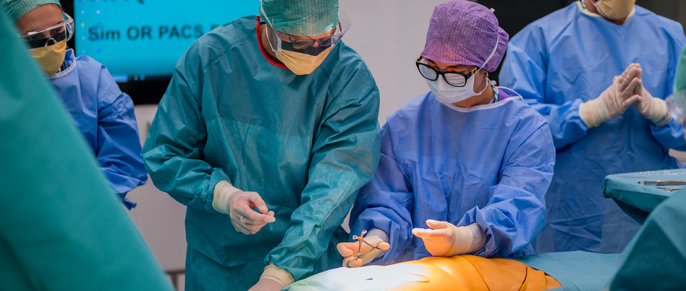 A medical student is instructed by a surgical technician in the OR-X on how to disinfect a patient before surgery.