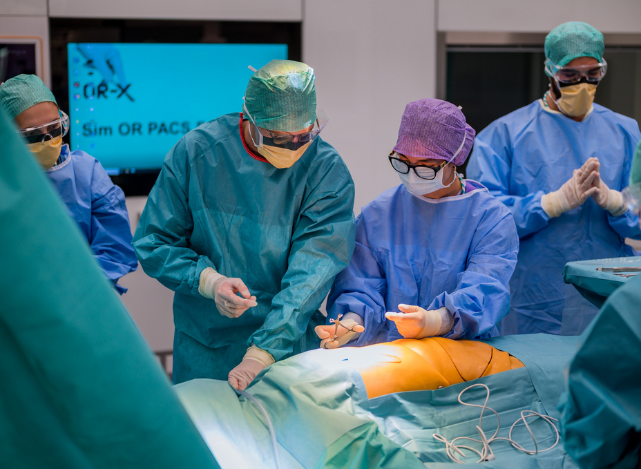 A medical student is instructed by a surgical technician in the OR-X on how to disinfect a patient before surgery.
