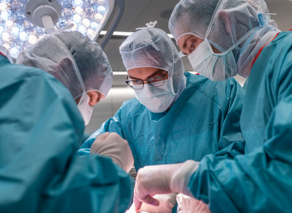 Three residents work in the OR-X at an operating table and access the ankle joint